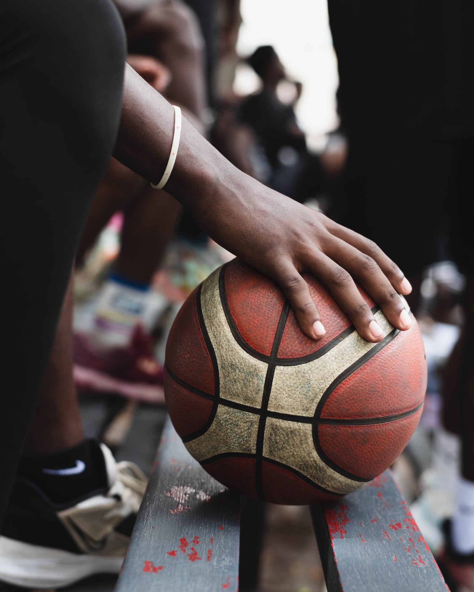 A worn basketball resting on a courtside bench