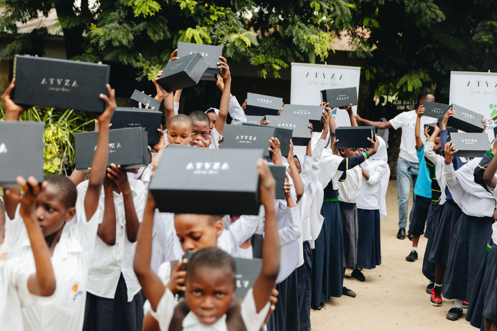 Students raising boxes of new school shoes above their heads