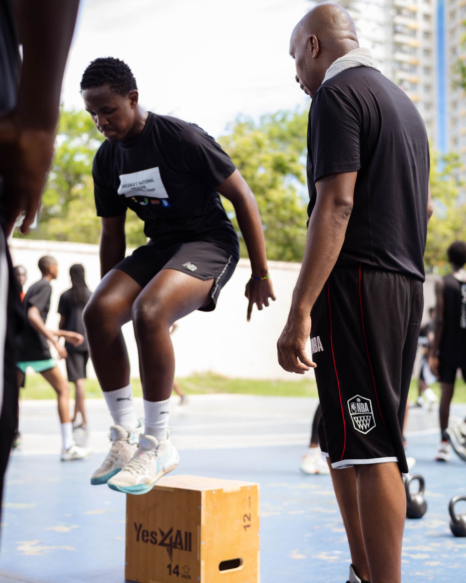 An athlete doing box jumps while a coach watches
