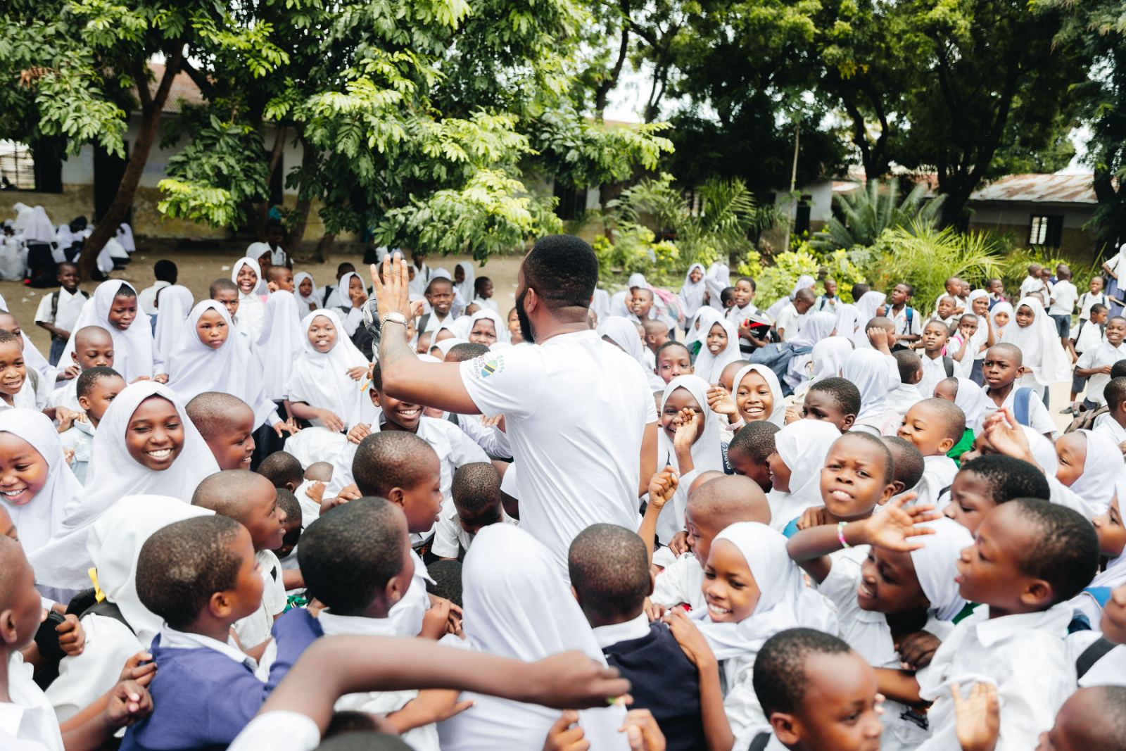 Founder Alpha Kisusi greeting students in a Tanzanian schoolyard