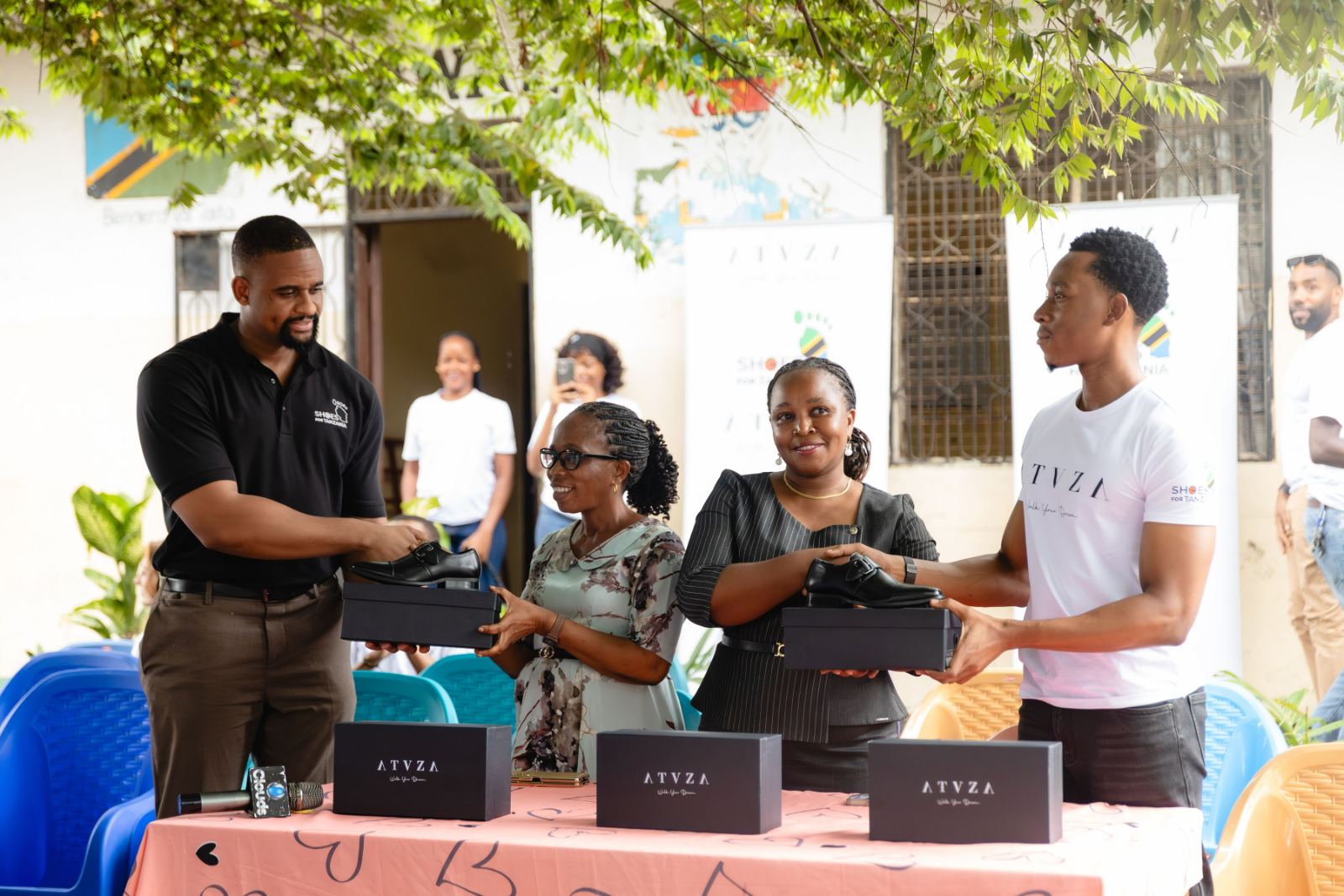 ATUZA and Shoes For Tanzania representatives handing boxes of school shoes to teachers