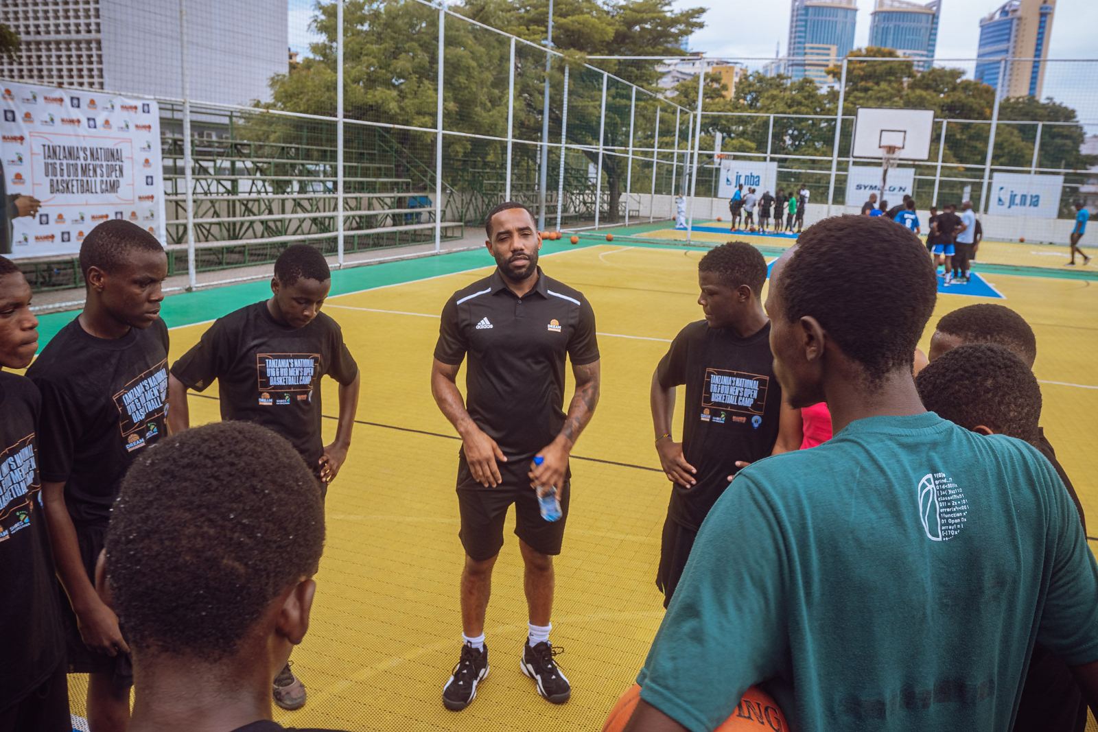 A coach talking with athletes on an outdoor court
